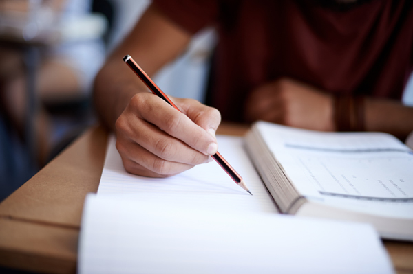 Closeup shot of a young man writing on a note pad Closeup shot of a young man writing on a note pad